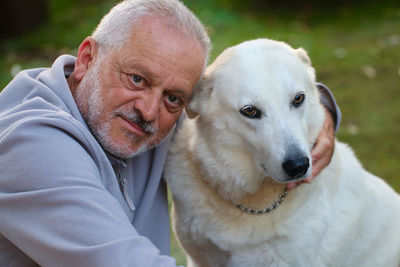 Portrait of man sitting with dog on land