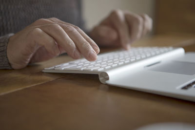 Close-up of man using laptop on table