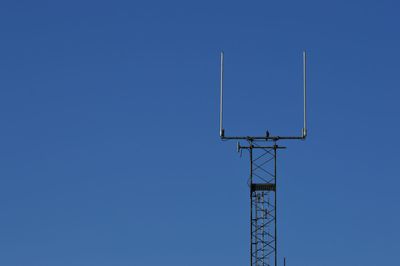 Low angle view of antenna against clear blue sky