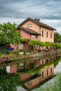 Houses by lake against sky