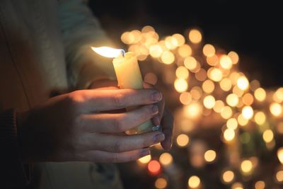 Close-up of hand holding illuminated candles