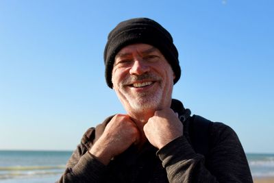 Portrait of smiling man at beach against clear sky