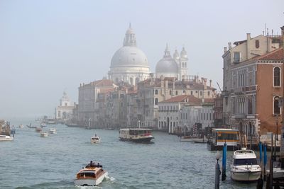 Boats sailing in city against clear sky