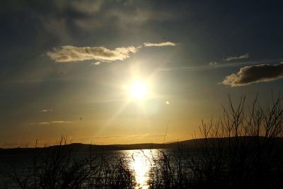 Sun shining through clouds over river