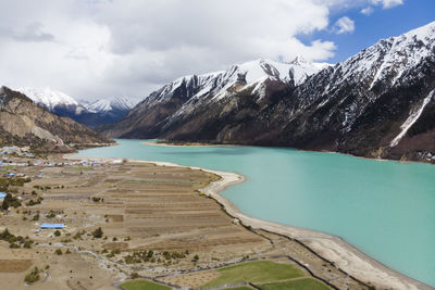 Scenic view of lake by snowcapped mountains against sky