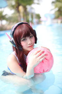 Portrait of young woman with arms raised in swimming pool