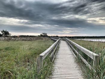 Boardwalk on field against sky