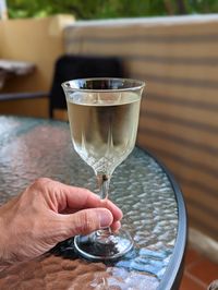 Cropped hand of man holding wineglass on table