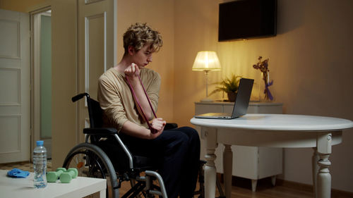 Young man exercising while sitting on wheelchair