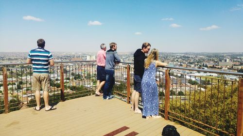 People on railing against sky