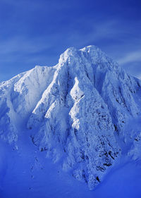 Scenic view of snowcapped mountain against blue sky