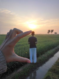 Man standing on field against sky during sunset