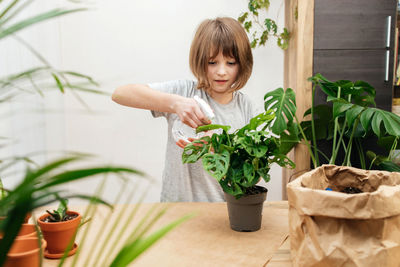 A teenage girl sprays home flowers from a spray bottle at home. house plant care. hobby 