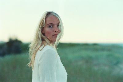 Portrait of young woman standing on field