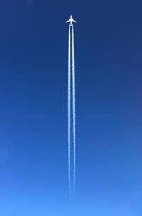 Low angle view of vapor trail against blue sky