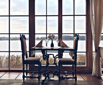 Empty chairs and table by window at home