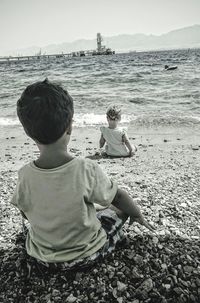 Rear view of woman sitting on beach