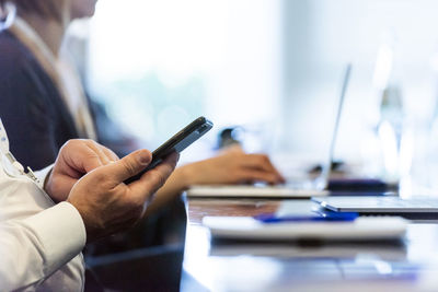 Midsection of man using mobile phone on table