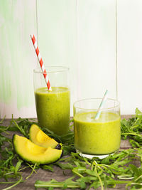 Smoothie in glasses and arugula on table