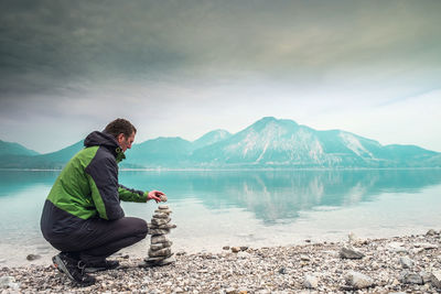 Cairn building. hiker built rock cairn from sharp dolomit stone at alpine lake. spring european alps