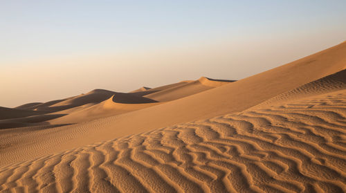 Sand dune in desert against clear sky during sunset