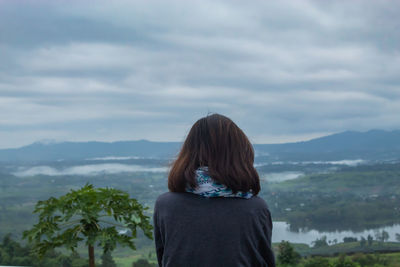 Rear view of woman looking at mountains against sky