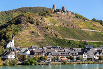 Scenic view of townscape by mountain against sky