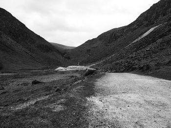 Road leading towards mountains against sky