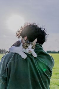 Rear view of man with cat standing against sky
