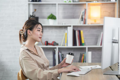 Young woman using mobile phone while standing in library