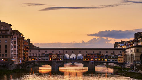 Arch bridge over river against sky in city