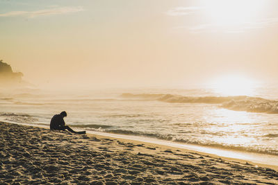 Silhouette man on beach against sky during sunset