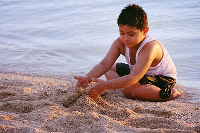 Boy playing with sand at beach