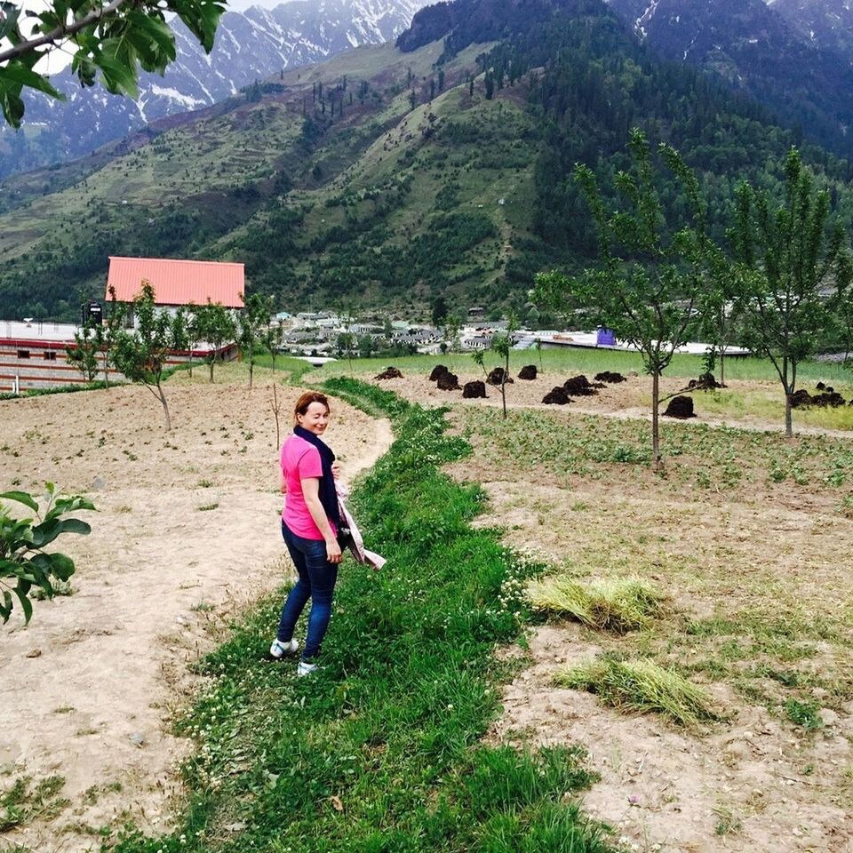 full length, lifestyles, leisure activity, casual clothing, mountain, grass, tree, rear view, walking, person, building exterior, built structure, nature, day, sunlight, landscape, standing