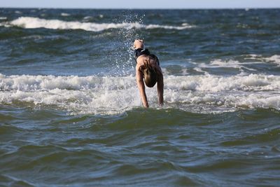 Full length of shirtless man diving into sea