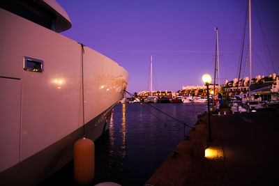 Sailboats moored in harbor against sky at night