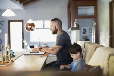Side view of father and son using technologies at dining table