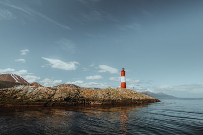 Lighthouse by sea against sky