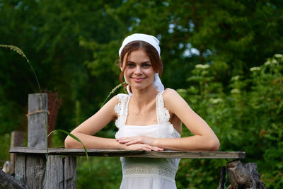 Portrait of young woman sitting on railing