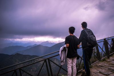 Rear view of couple standing on mountain against sky