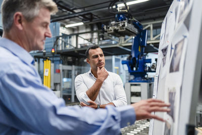 Businessman with male colleague discussing about business strategy in industry