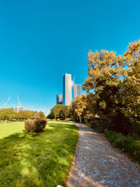 Walkway by trees against blue sky