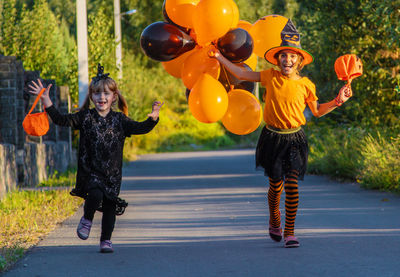 Full length of kids walking on road with halloween costume