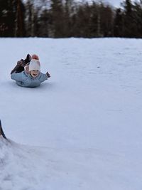 Rear view of man sitting on snow covered field