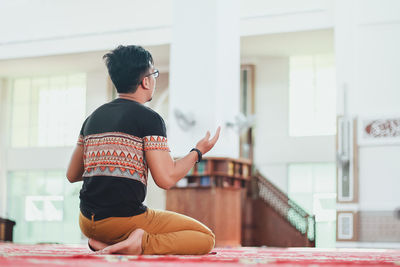 Rear view of man praying at mosque