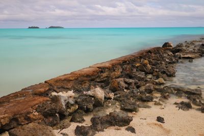 Scenic view of rocks on beach against sky