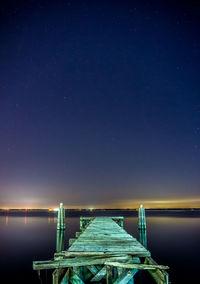 Pier over sea against blue sky at dusk
