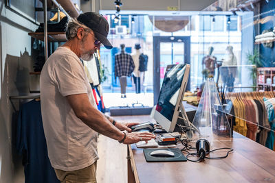 Side view of clothing store owner checking sales on computer person