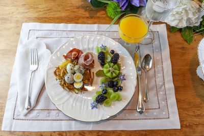 Quail eggs on a hashbrown potato nest with prosciutto and decorative fruit.