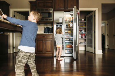 Boy standing by refrigerator with brother at home